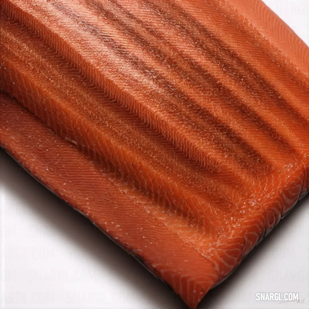 Piece of salmon is laying on a white surface with a white background and a red stripe on the side