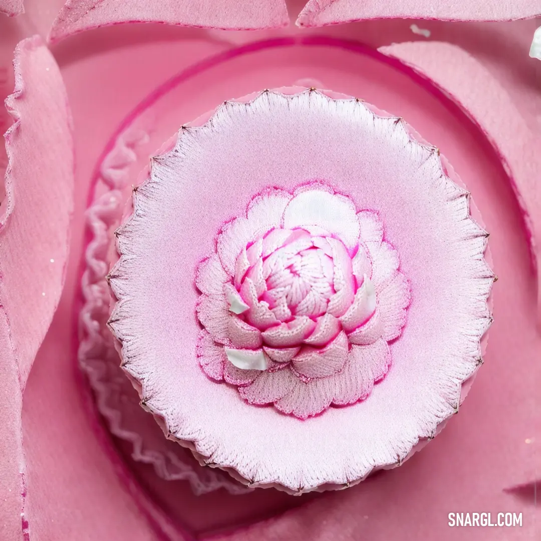 Pink flower in a white bowl on a pink surface with pink petals on it