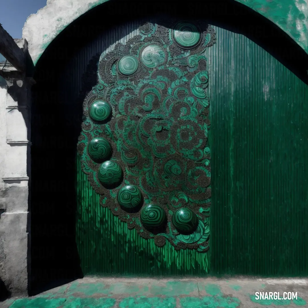 Green door with a decorative design on it's side and a stone wall behind it with a doorway