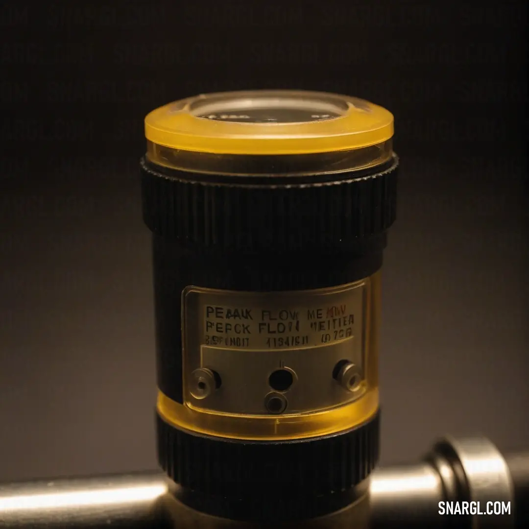 An intricate camera lens is balanced atop a robust metal pipe featuring a vibrant yellow cap, contrasting against a sleek black background, creating a striking visual.