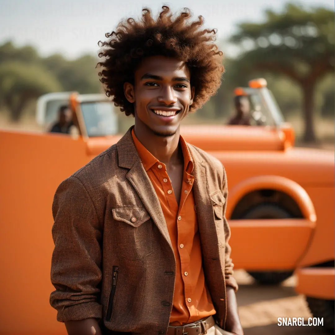 Man with a afro standing in front of a truck smiling at the camera with a smile on his face