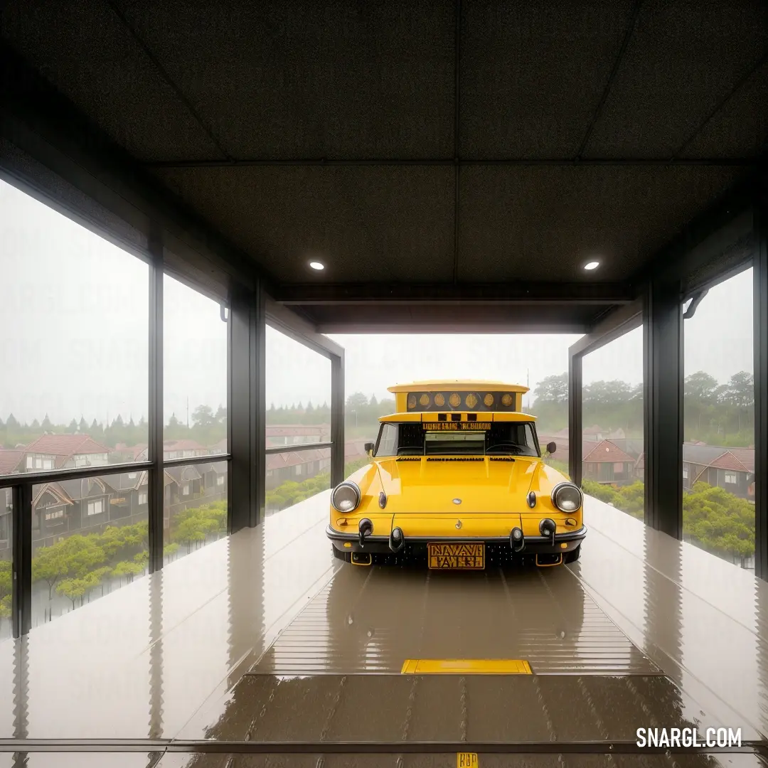 Saffron color example: Yellow school bus parked in a parking garage with a view of a field and houses in the background