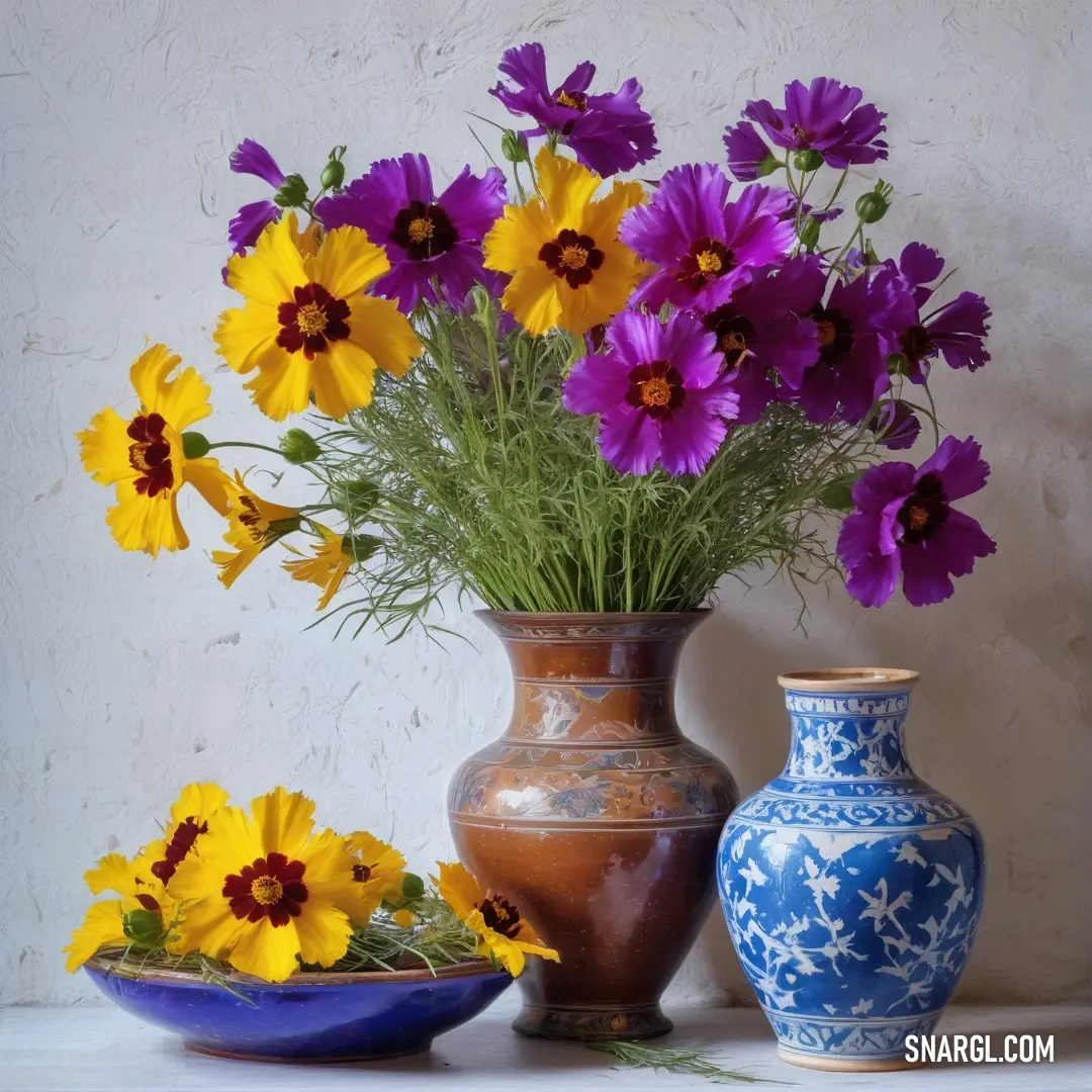 Vase of flowers and a bowl of flowers on a table with a wall in the background. Example of Sana color.