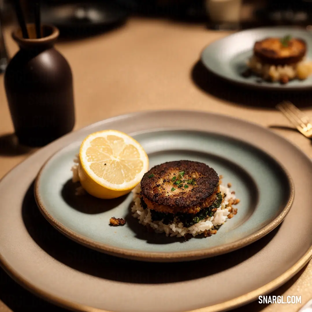 Plate with a crab cake and a lemon slice on it on a table with a fork and knife