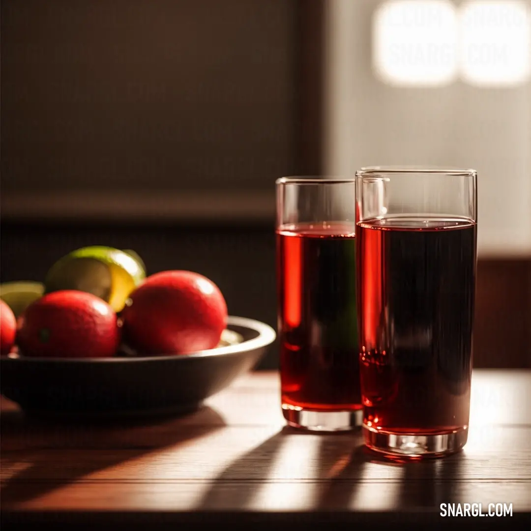 Two glasses of red wine sit on a table next to a bowl of fruit and a bowl of apples. Color #FF2400.