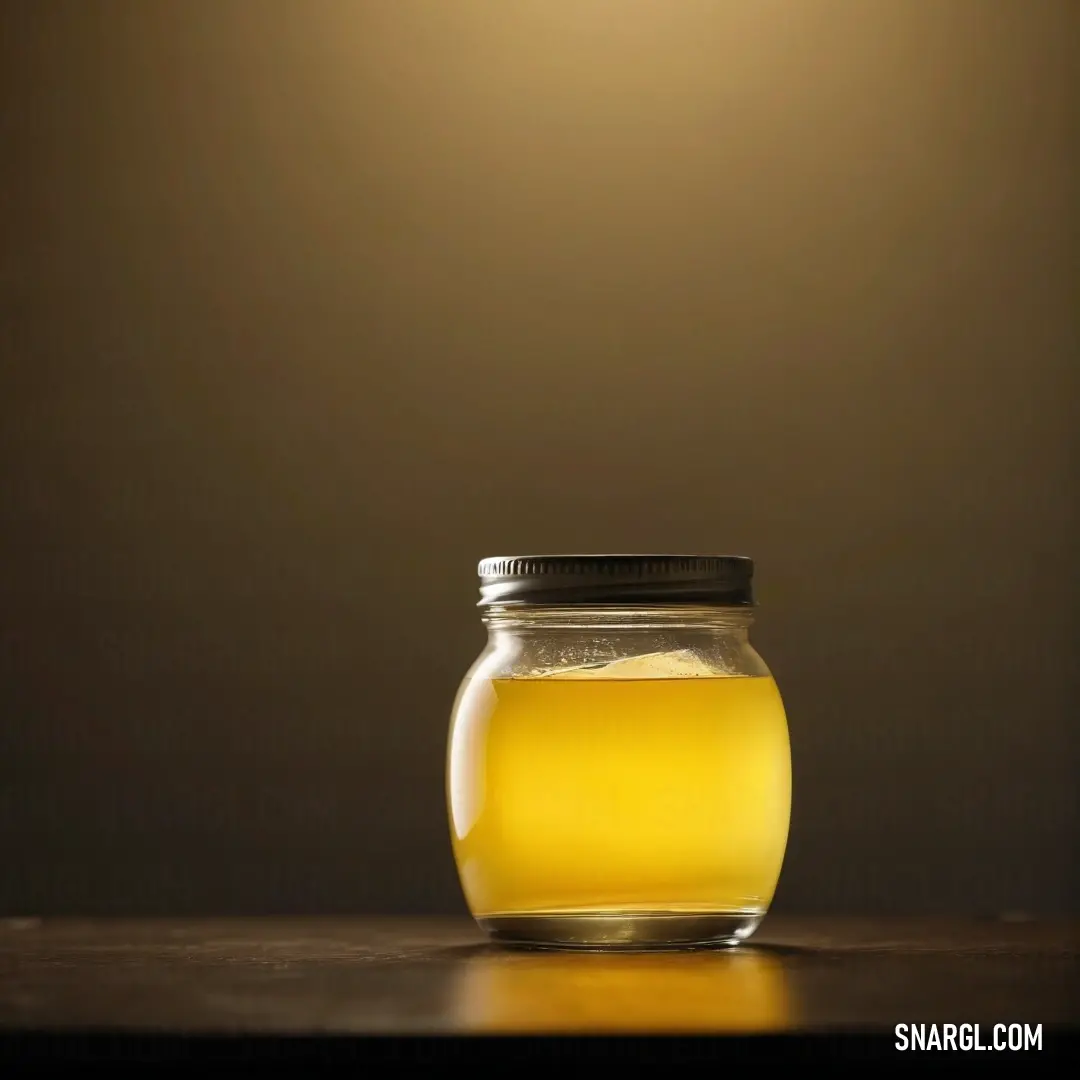 School bus yellow color example: Jar of honey on a table with a light shining on it's side and a black lid