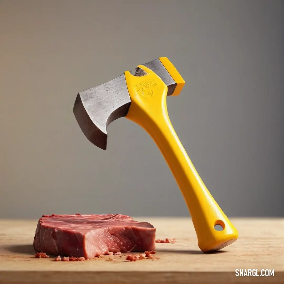 School bus yellow color. Yellow handled hammer hitting a piece of meat on a wooden table with a gray background