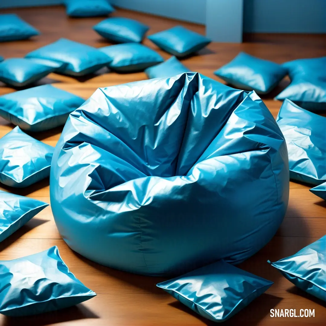 Large blue bean bag chair surrounded by blue pillows on a wooden floor with a few blue pillows scattered around it