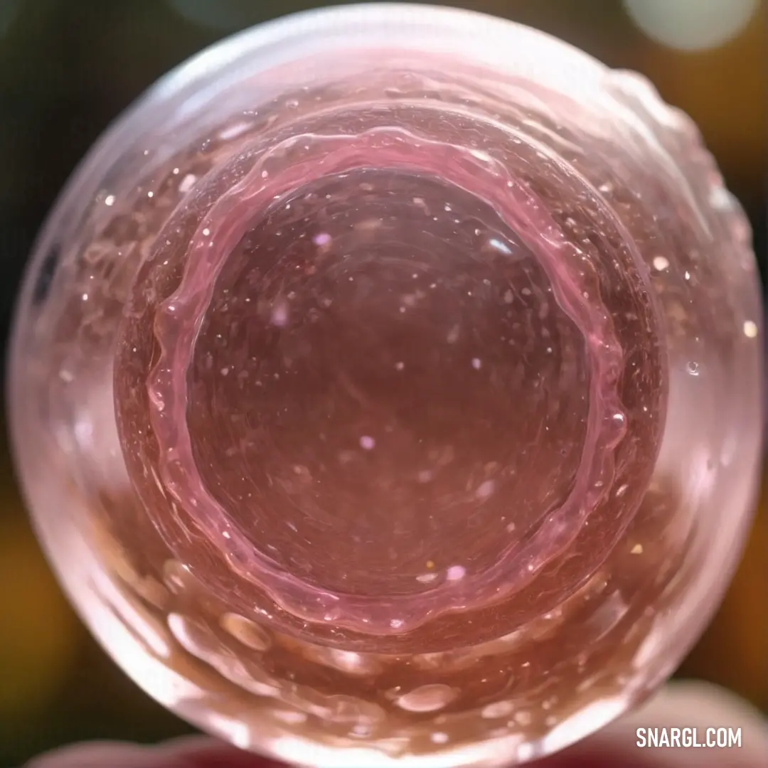 Sky magenta color example: Close up of a pink substance inside a glass cup with water droplets on it and a blurry background