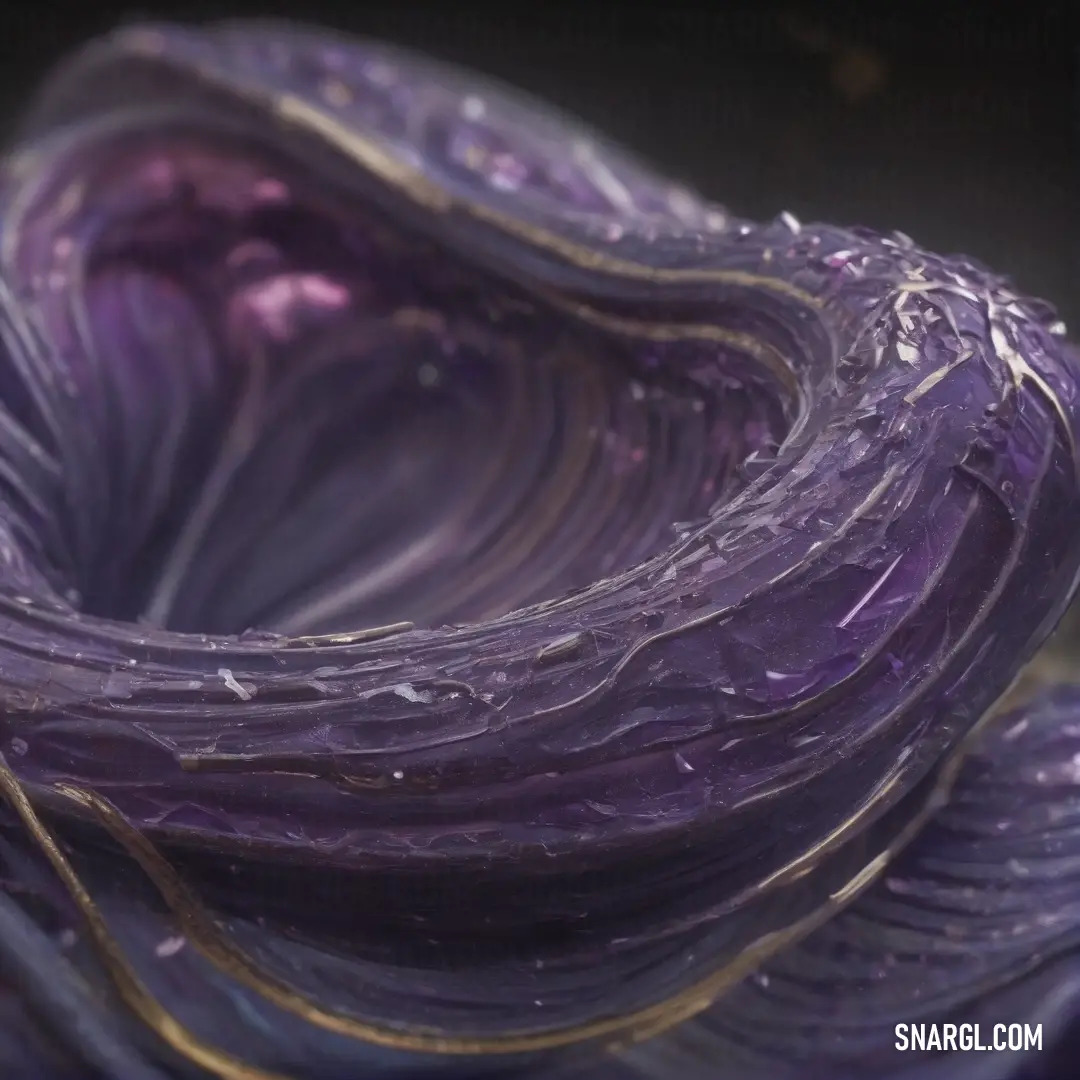 A close-up of a purple flower, its petals adorned with delicate water droplets and golden accents. The soft, rich colors of the flower contrast beautifully with the cool slate gray tones in the background.