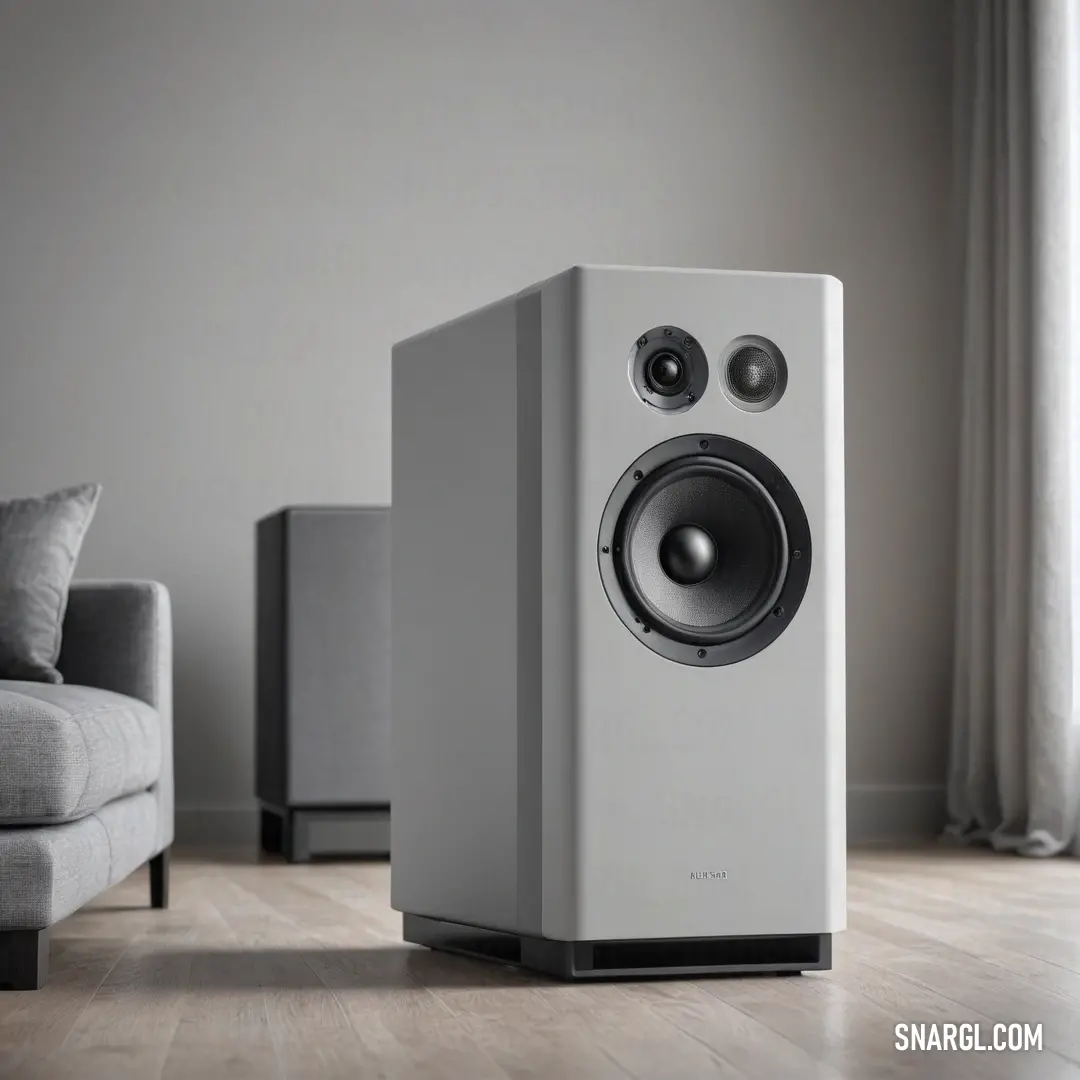 A pristine white speaker elegantly placed on a polished wooden floor, surrounded by a cozy couch and chair. The inviting atmosphere adds comfort and charm to any room, enhancing your auditory experience.