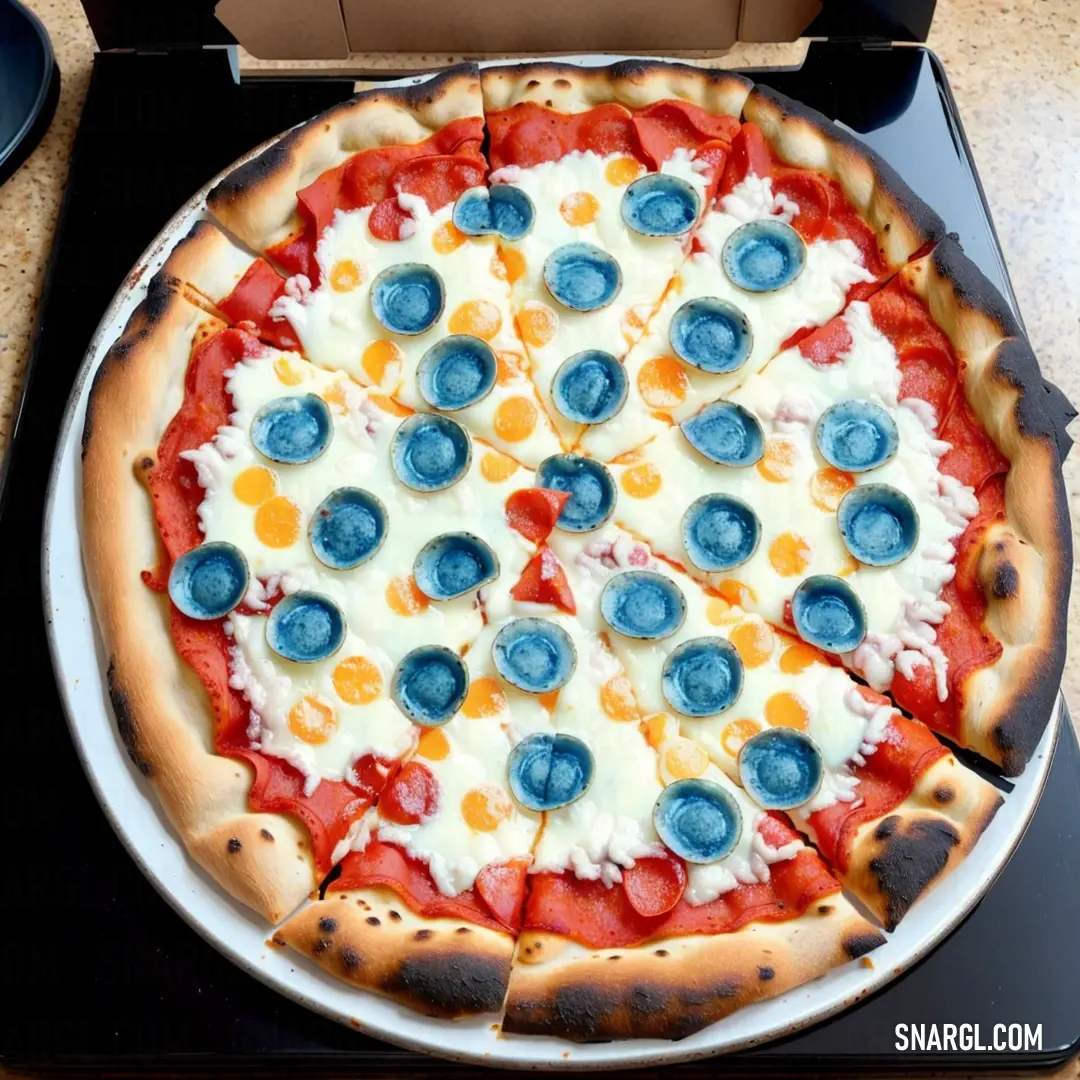 Pizza with blueberries and cheese on a stove top with a box of pizza in the background on a table