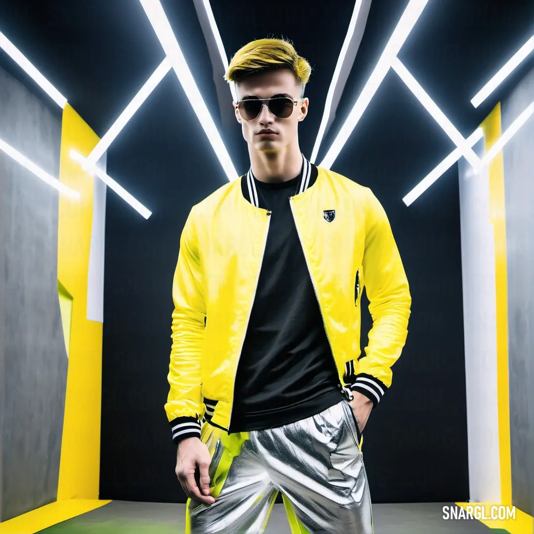 Man in a yellow jacket and silver pants standing in a room with neon lights on the ceiling and a black shirt on