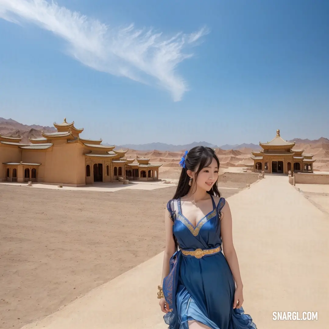 Woman in a blue dress standing in front of a desert area with buildings in the background