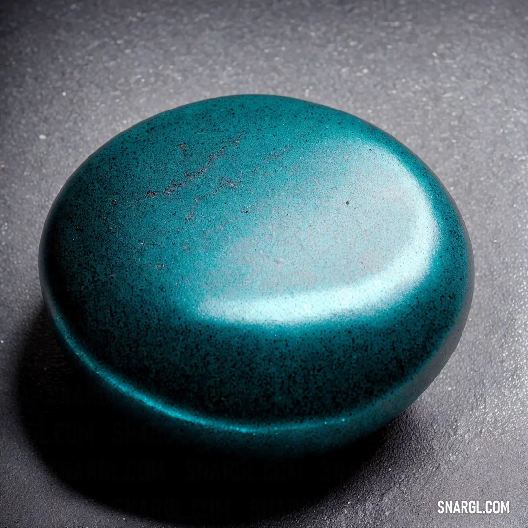 Blue round object on a table top with a black background and a black spot in the middle