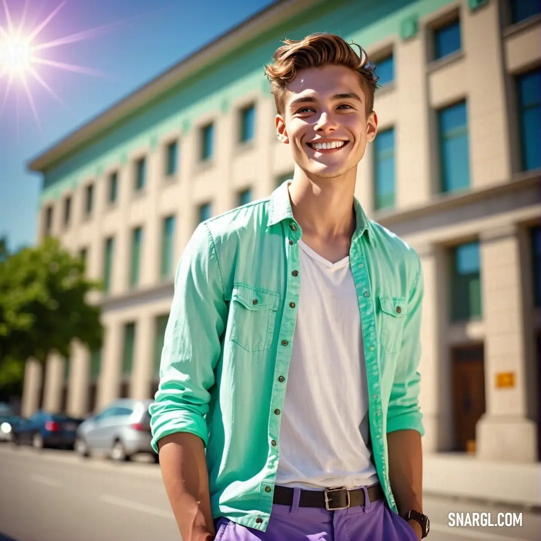 Man standing in front of a building smiling at the camera with a green shirt on and purple pants