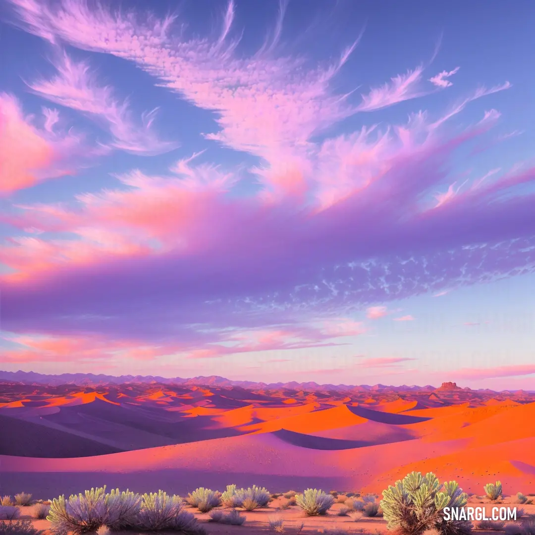 Desert landscape with a pink sky and clouds above it and a few bushes in the foreground