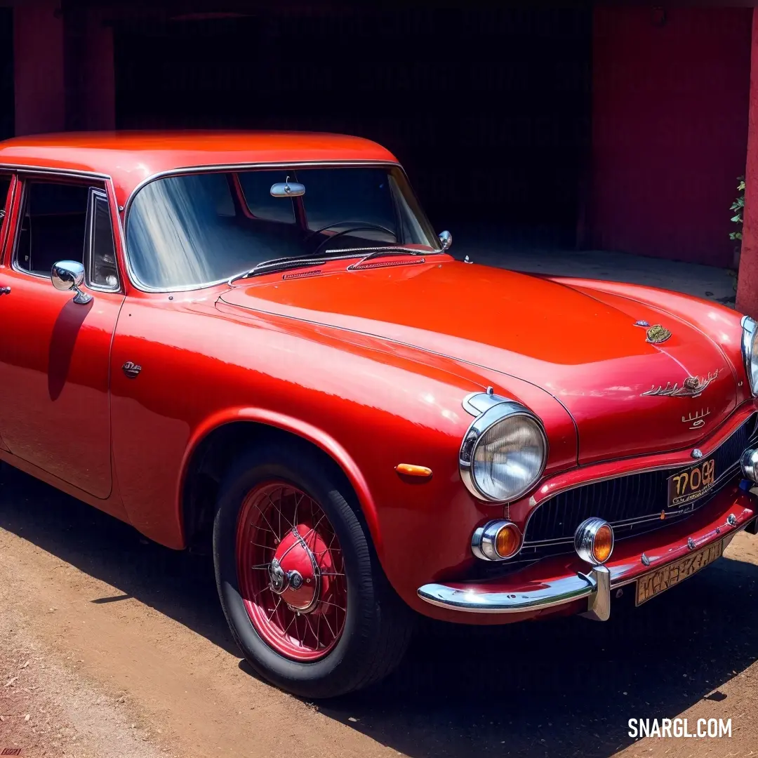 Red car parked in front of a garage door with a red wall behind it