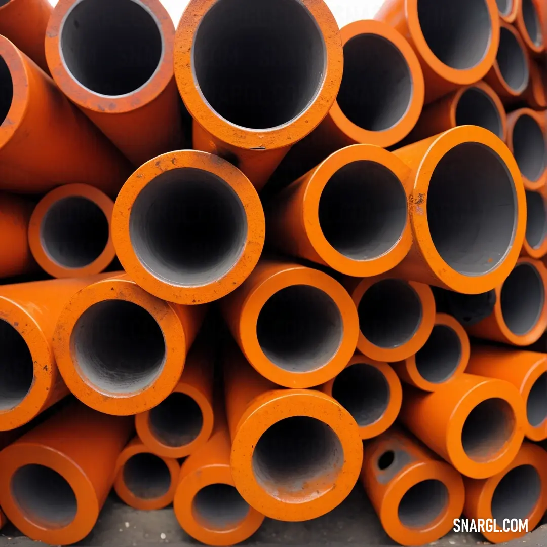 An impressive stack of orange pipes rests on a floor beside a wall lined with other pipes, creating an industrial look that showcases the materials and engineering that embody the heart of construction projects.