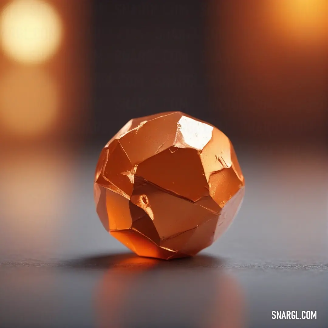 A shiny orange object sits on a table next to a candle holder, the deep orange hue casting a bright contrast against its surroundings. The object’s smooth surface catches the light, drawing attention with its vivid color.