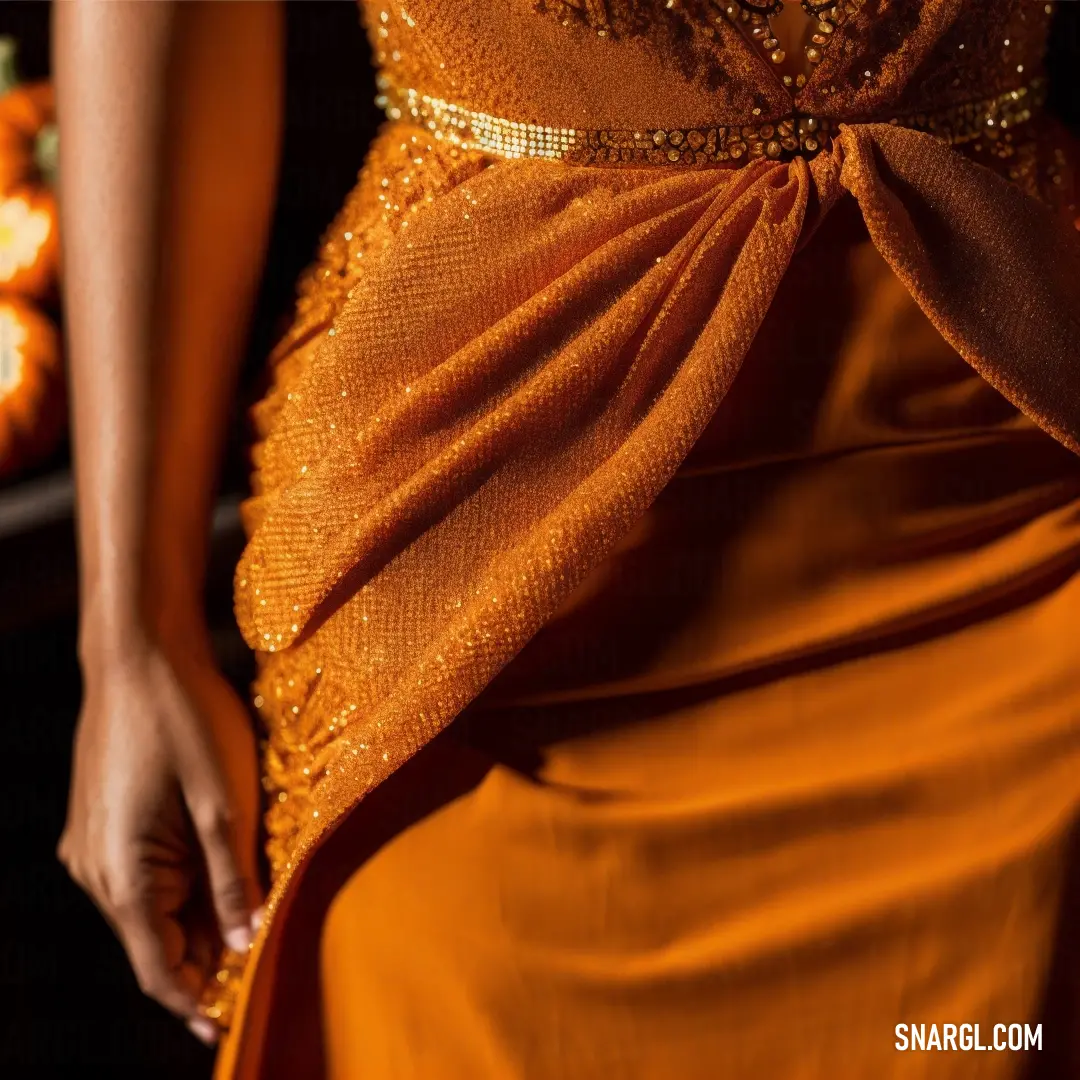 Woman in a dress with a gold sash around her waist and a pumpkin in the background. Color #CD5700.