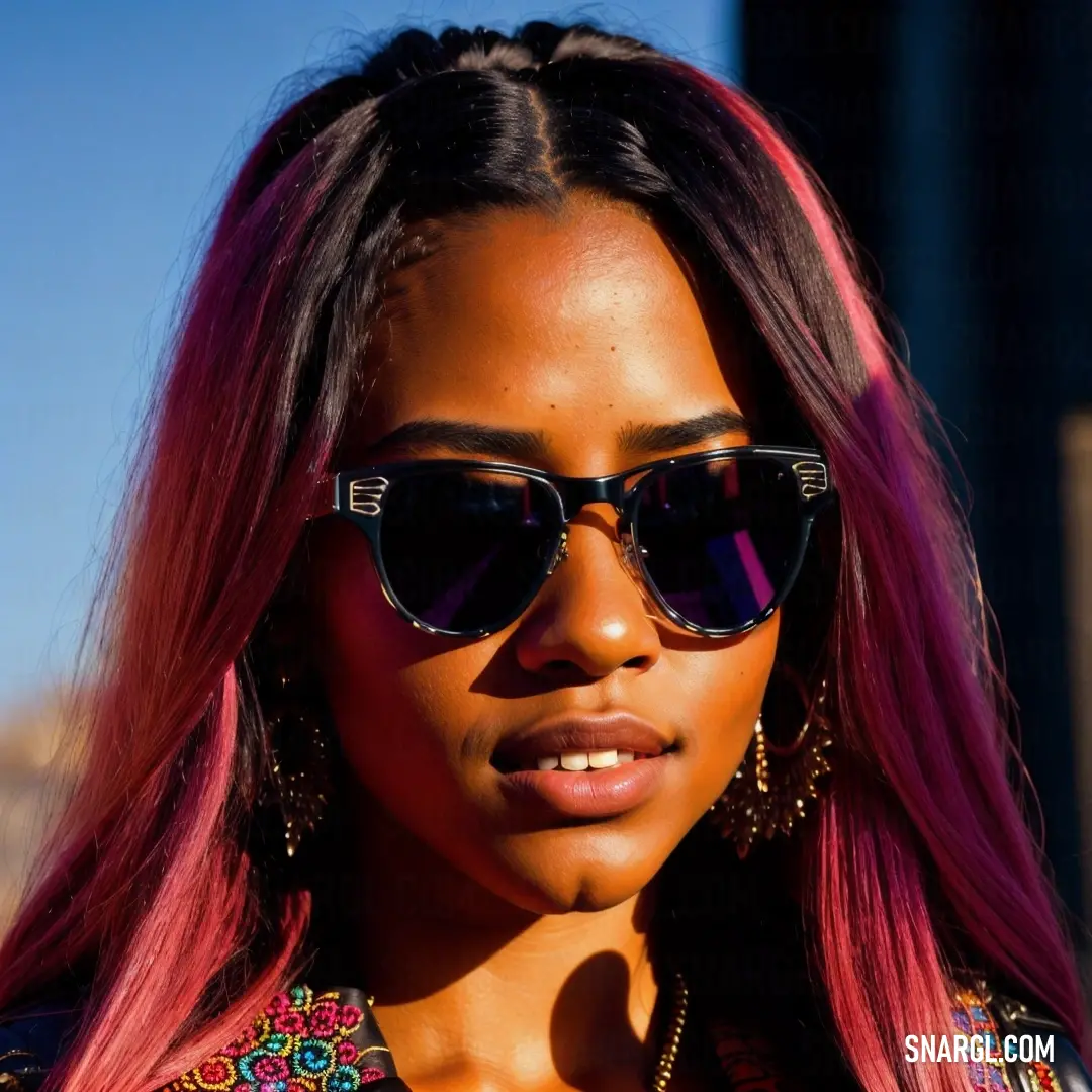 Woman with pink hair and sunglasses on her face and wearing a colorful shirt and earrings and a necklace