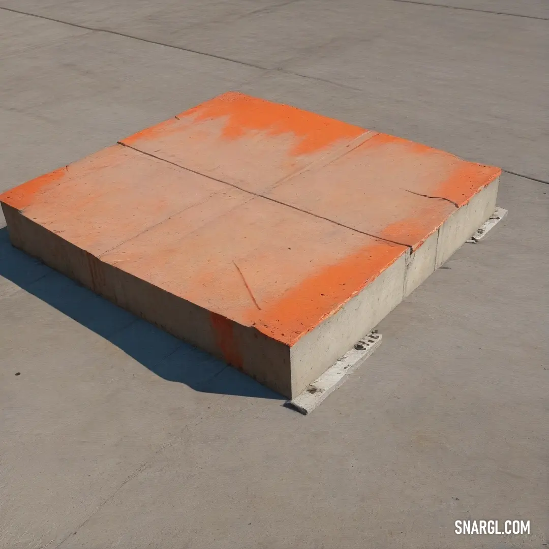 Concrete block on top of a cement floor next to a parking lot with a skateboard on it. Example of RGB 255,99,71 color.