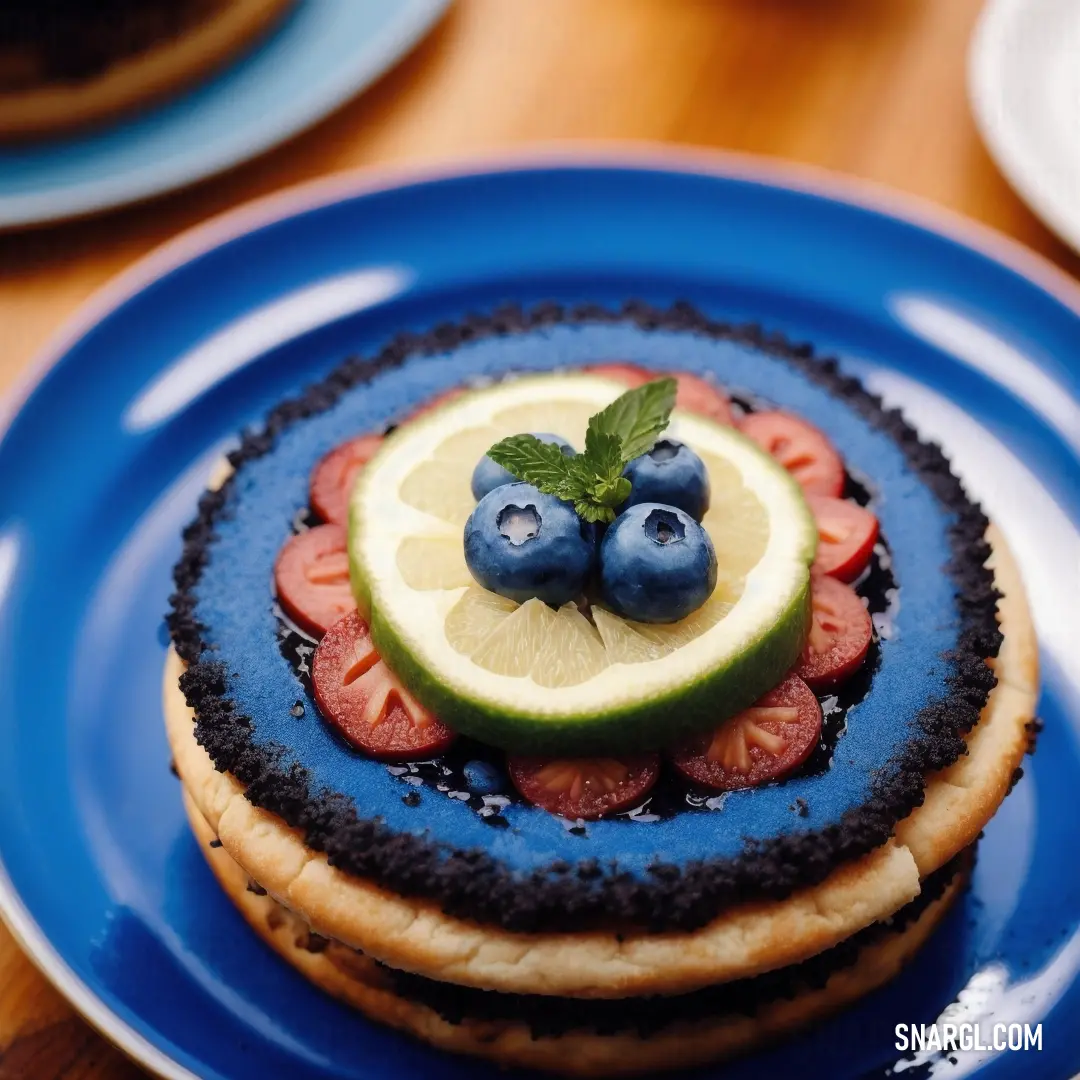 Blue plate topped with a cake covered in fruit and a slice of lime on top of it on a wooden table