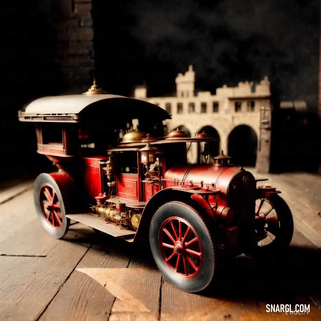 Toy fire truck on a wooden table in the dark with a castle in the background and a light shining on the floor