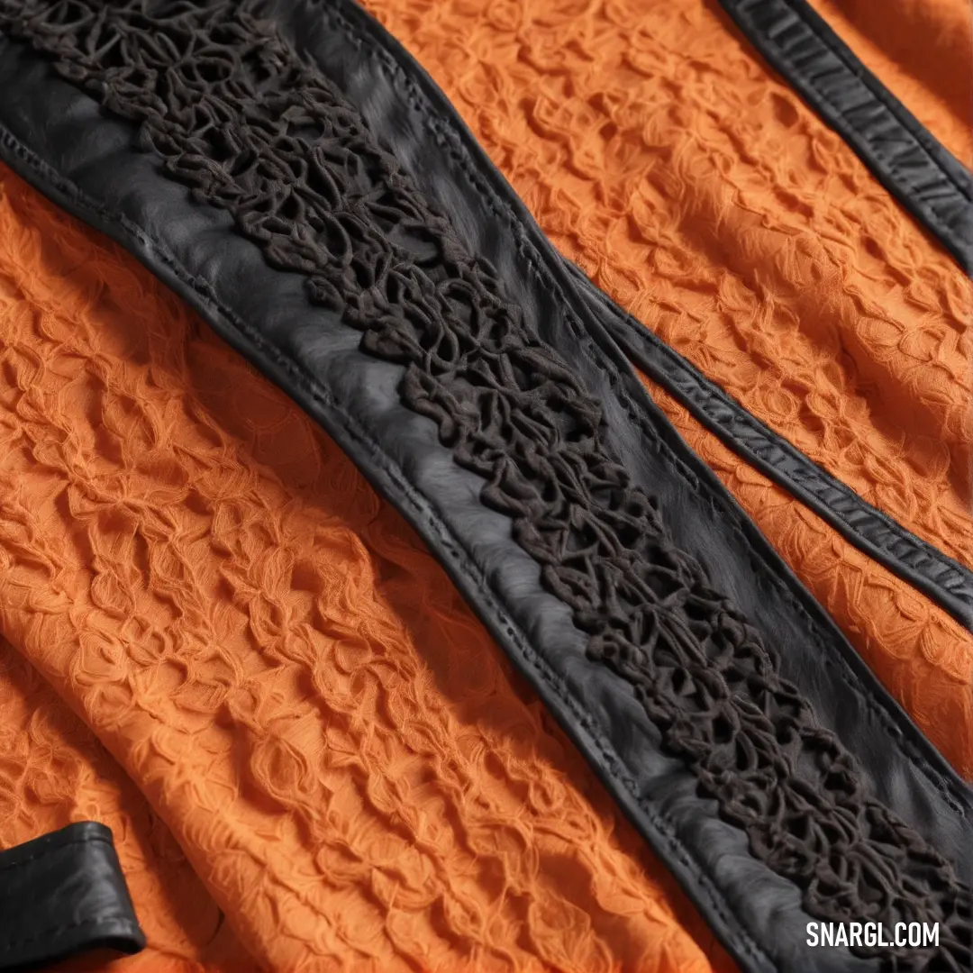 Ubuntu Orange color example: Close up of a black lace on an orange dress fabric with a black ribbon on it and a black leather belt
