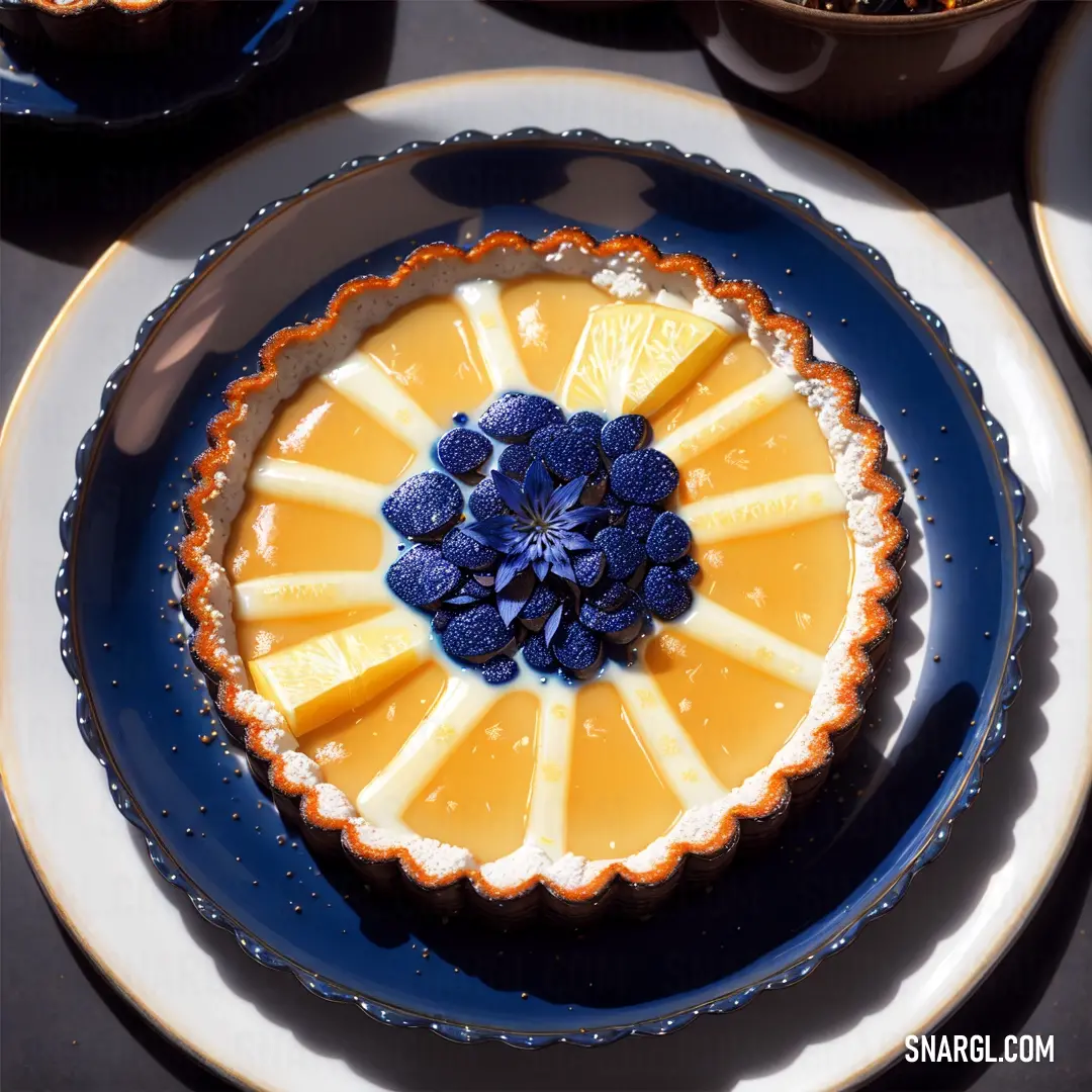 Pie with blue flowers on top of it on a plate with a bowl of fruit in the background