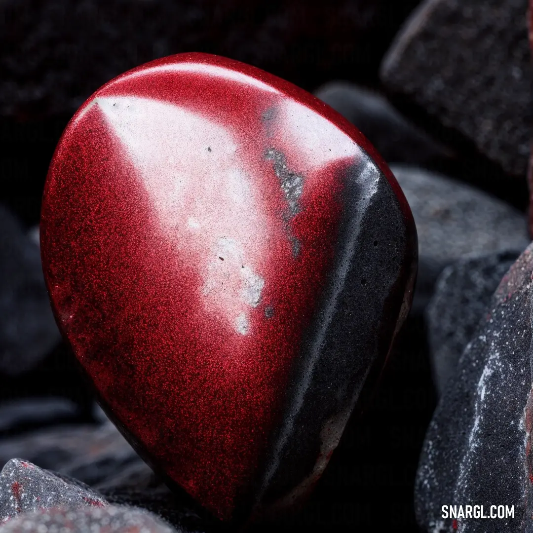 Heart shaped object on top of a pile of rocks and gravel. Example of RGB 174,32,41 color.
