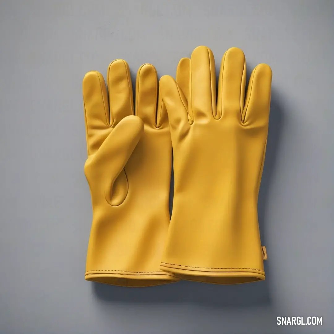 Pair of yellow gloves on a gray surface with a white background. Example of CMYK 0,23,85,12 color.