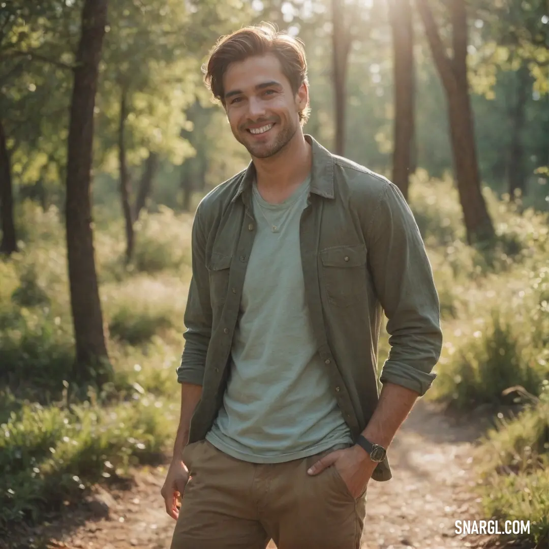 Man standing in the woods with his hands in his pockets and smiling at the camera with a smile on his face