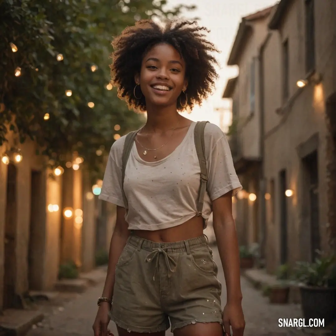 Woman with a backpack walking down a street with lights on the side of buildings behind her