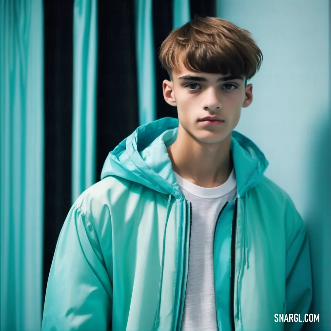 Young man in a blue jacket standing in front of a curtained wall with a white t - shirt underneath. Color CMYK 63,0,3,30.