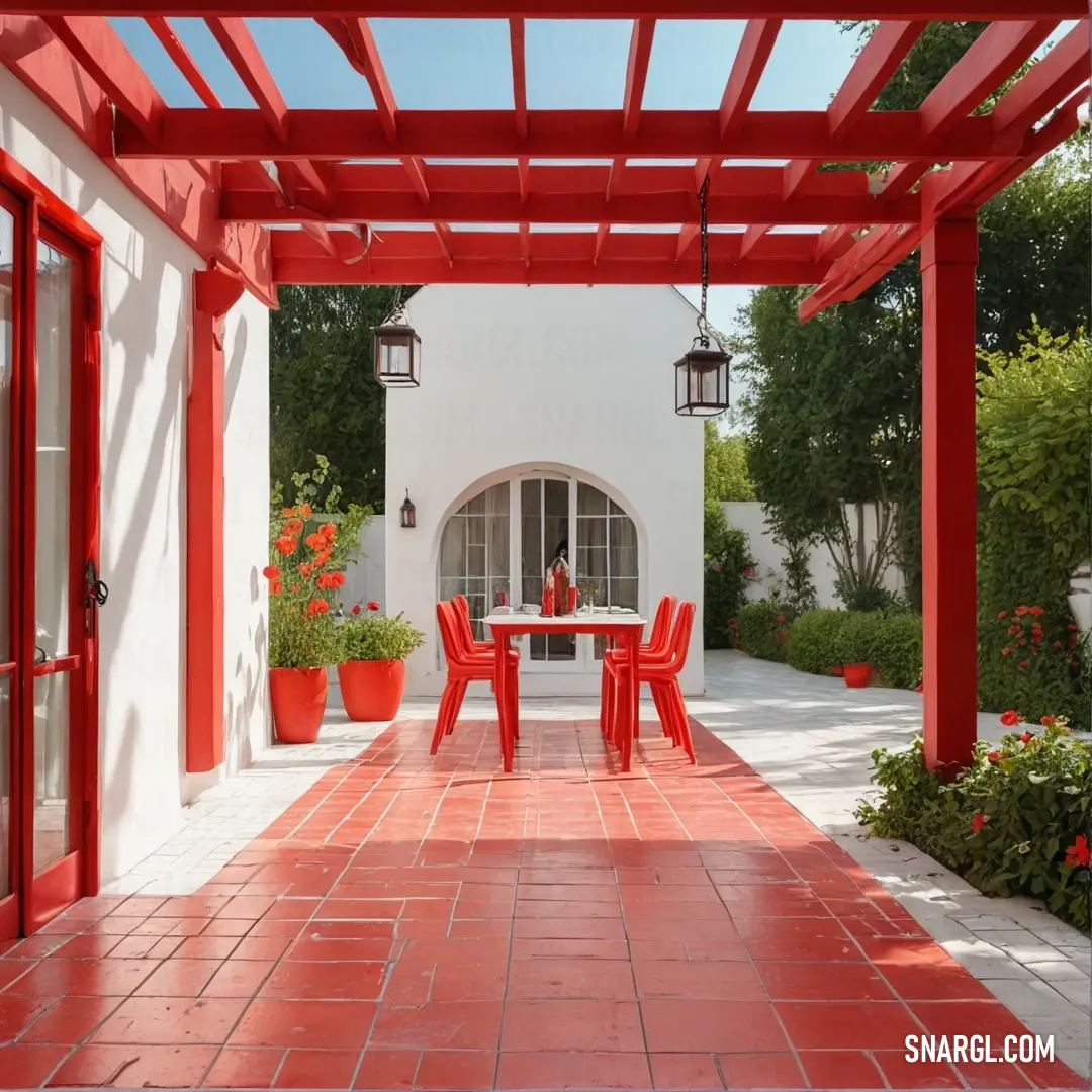 Red patio with a table and chairs and potted plants on the side of the house and a red door. Example of RGB 227,66,52 color.