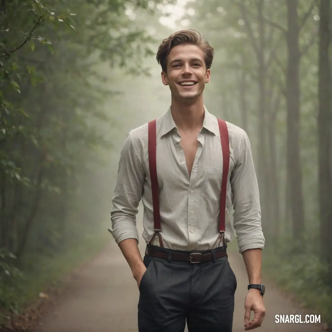 Man in suspenders and a shirt is smiling at the camera while standing on a path in the woods