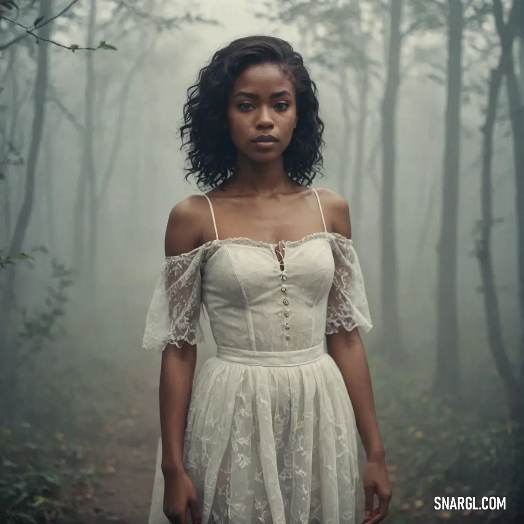 Woman in a white dress standing in a forest with foggy trees behind her