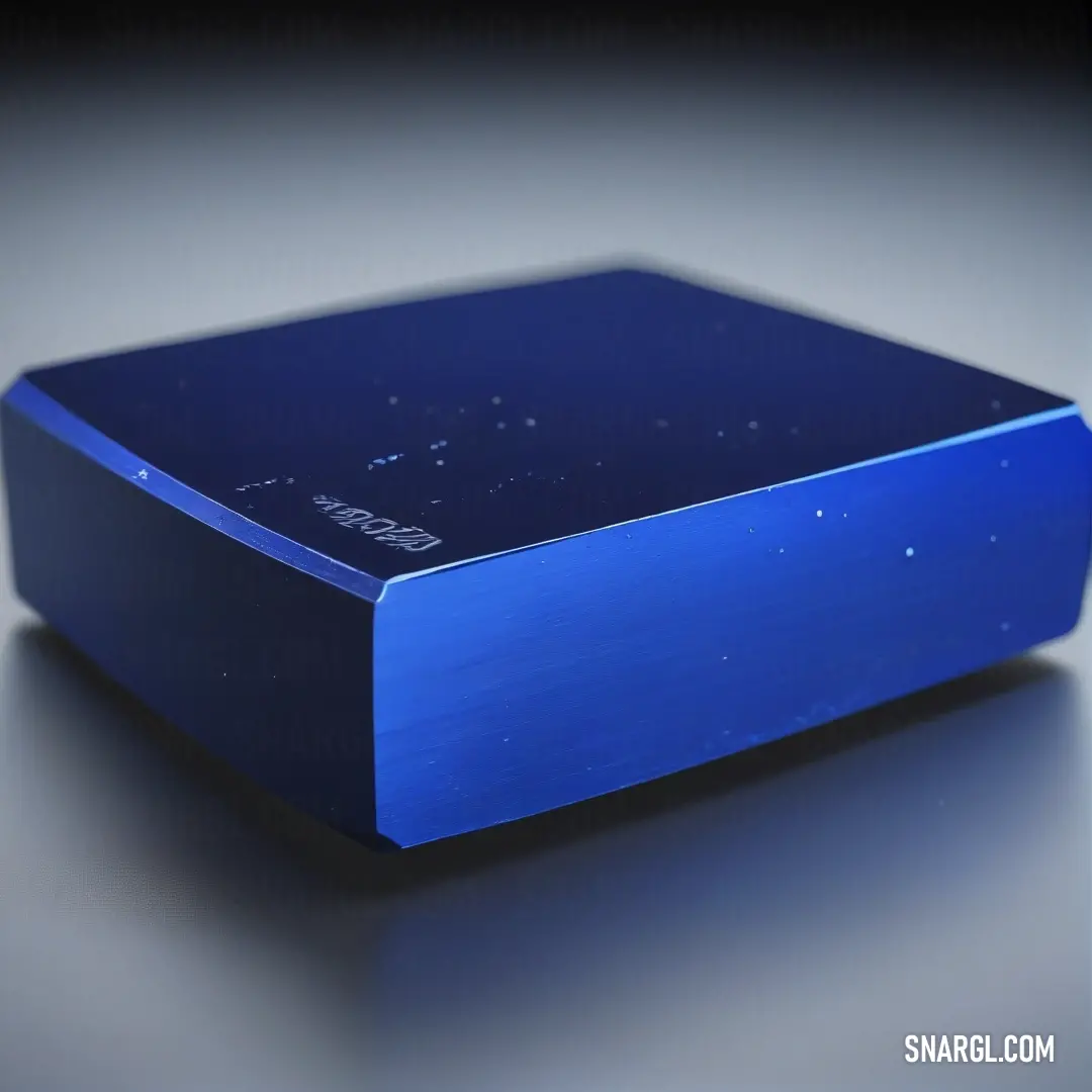 Blue box on top of a table next to a black background. Color RGB 50,74,178.