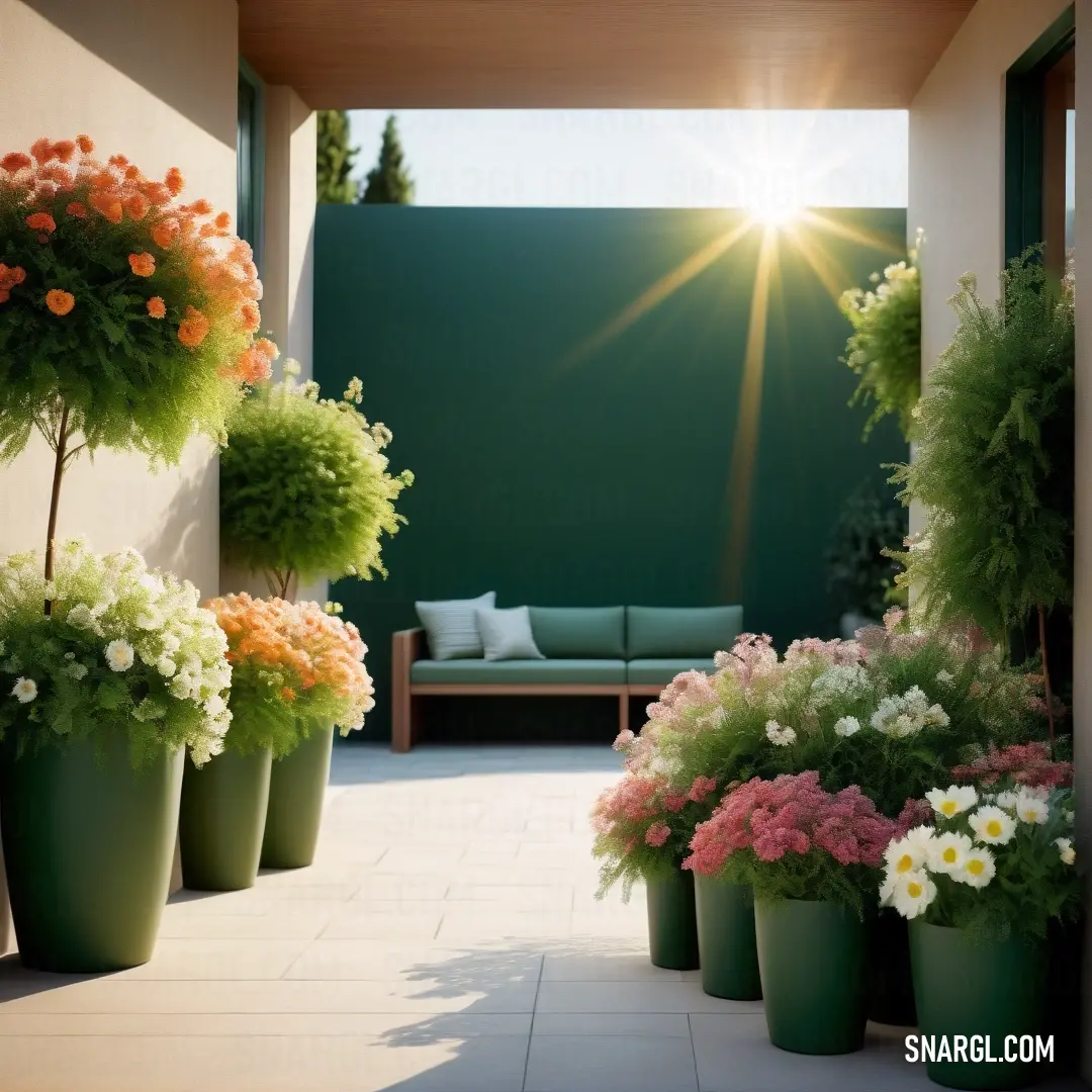 A stylish patio featuring a cozy couch surrounded by an array of colorful flowers, with a lush green wall acting as a backdrop. The combination of nature and modern furniture creates a serene outdoor retreat.