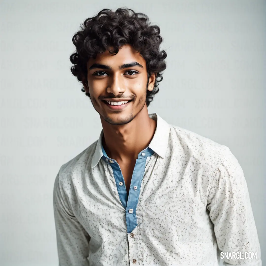 Man with curly hair and a smile on his face is smiling at the camera while wearing a white shirt