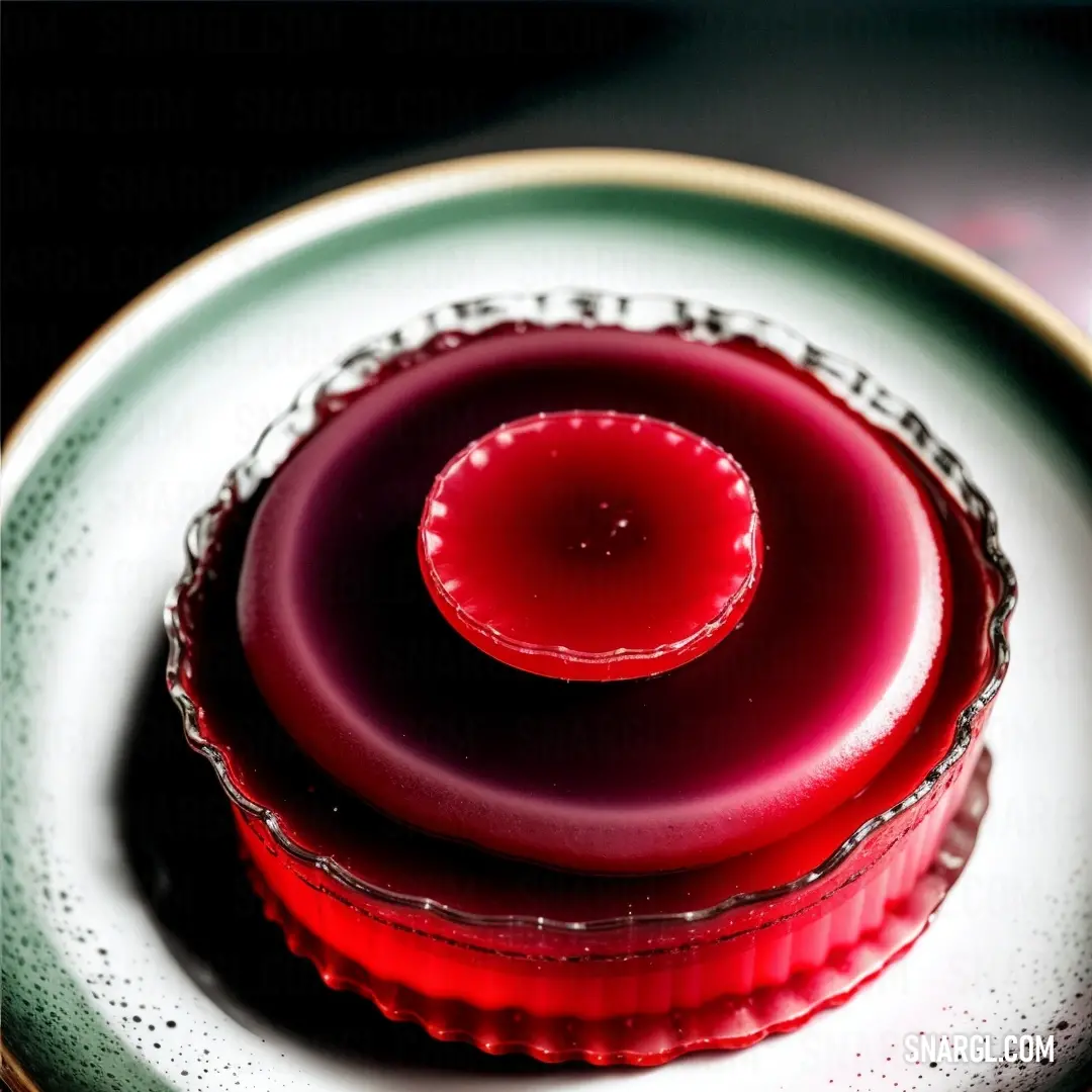 Red jelly is on a white plate on a tablecloth with a black background and a gold rim
