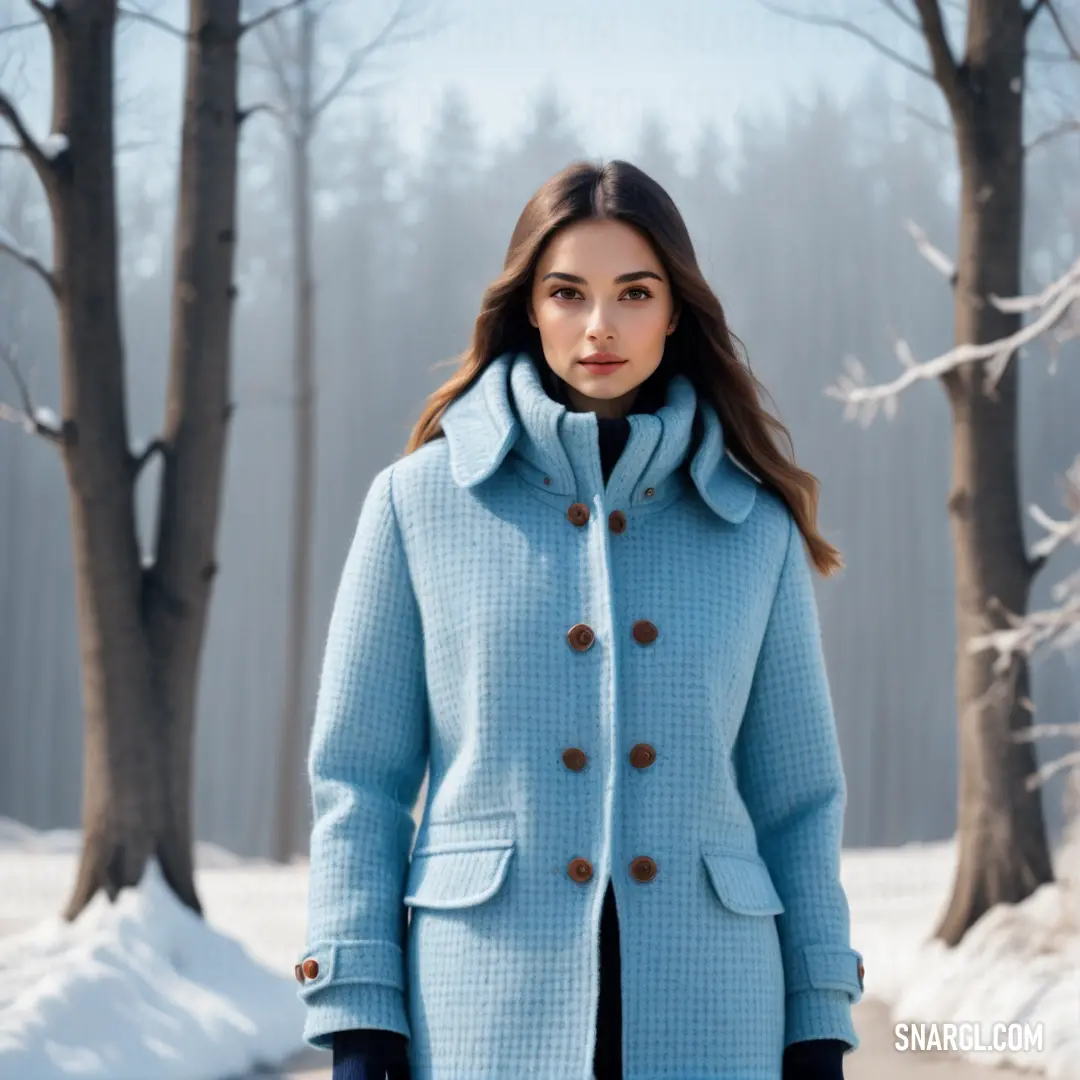 Woman in a blue coat standing in the snow in front of trees and snow covered ground with a snowboard