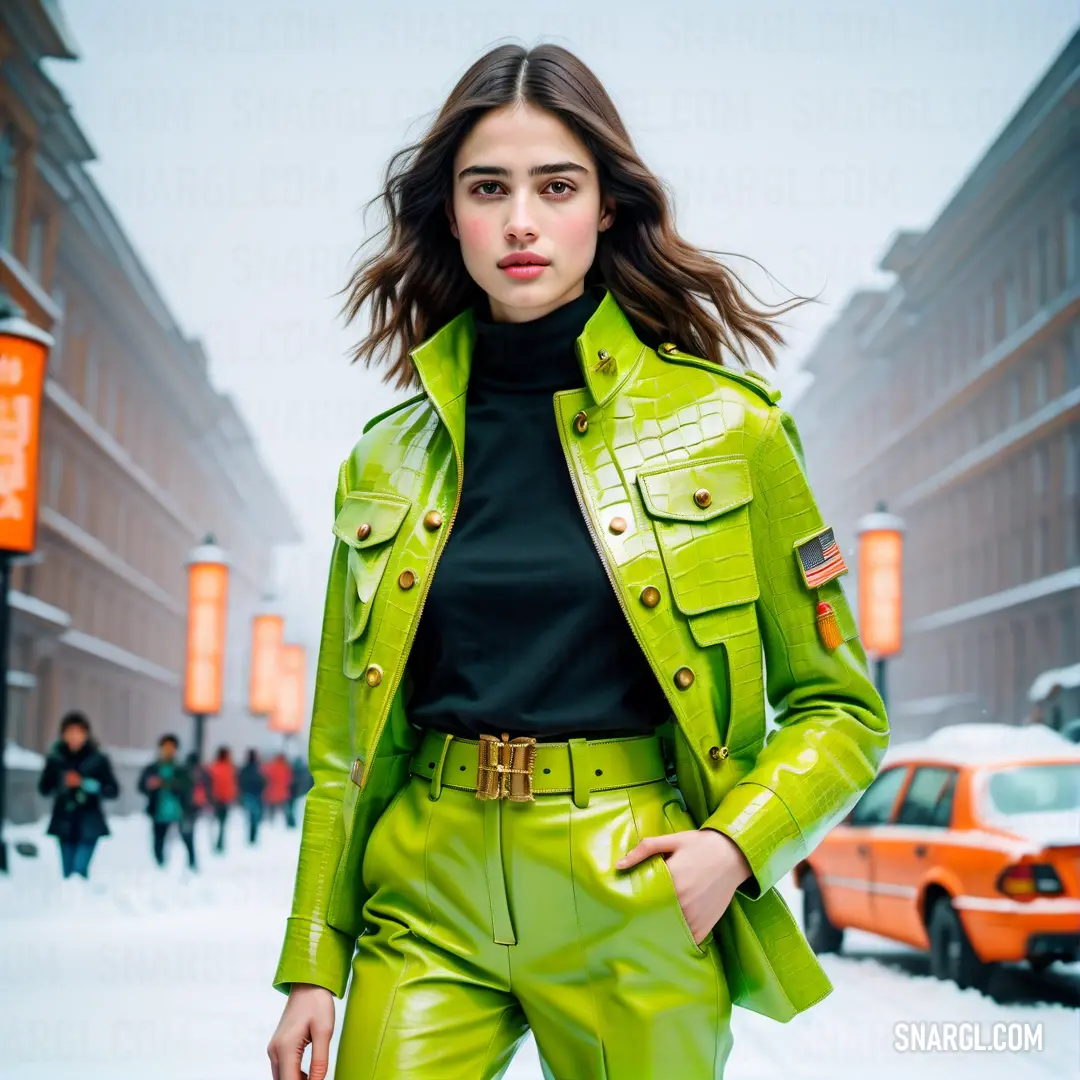 Woman in a green leather jacket and pants is walking down the street in the snow with a red car. Color #9ACD32.