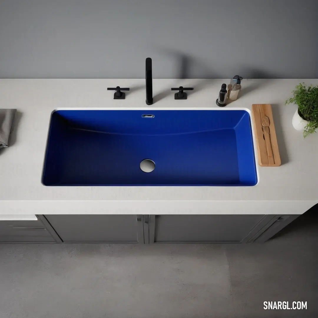 Blue sink on top of a white counter top next to a plant and a wooden cutting board. Example of #0014A8 color.