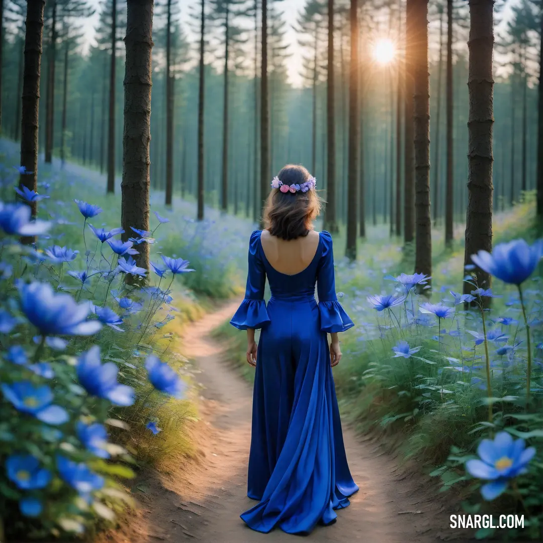 Woman in a blue dress walking through a forest of blue flowers with the sun shining through the trees. Color Zaffre.